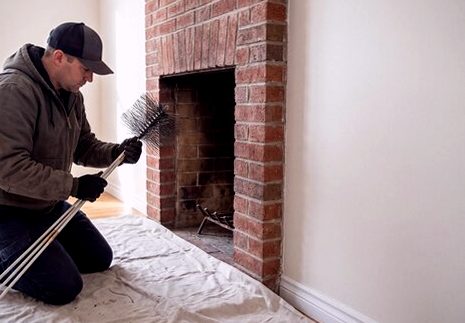 Hearth work staged on drop cloths before a brick fireplace